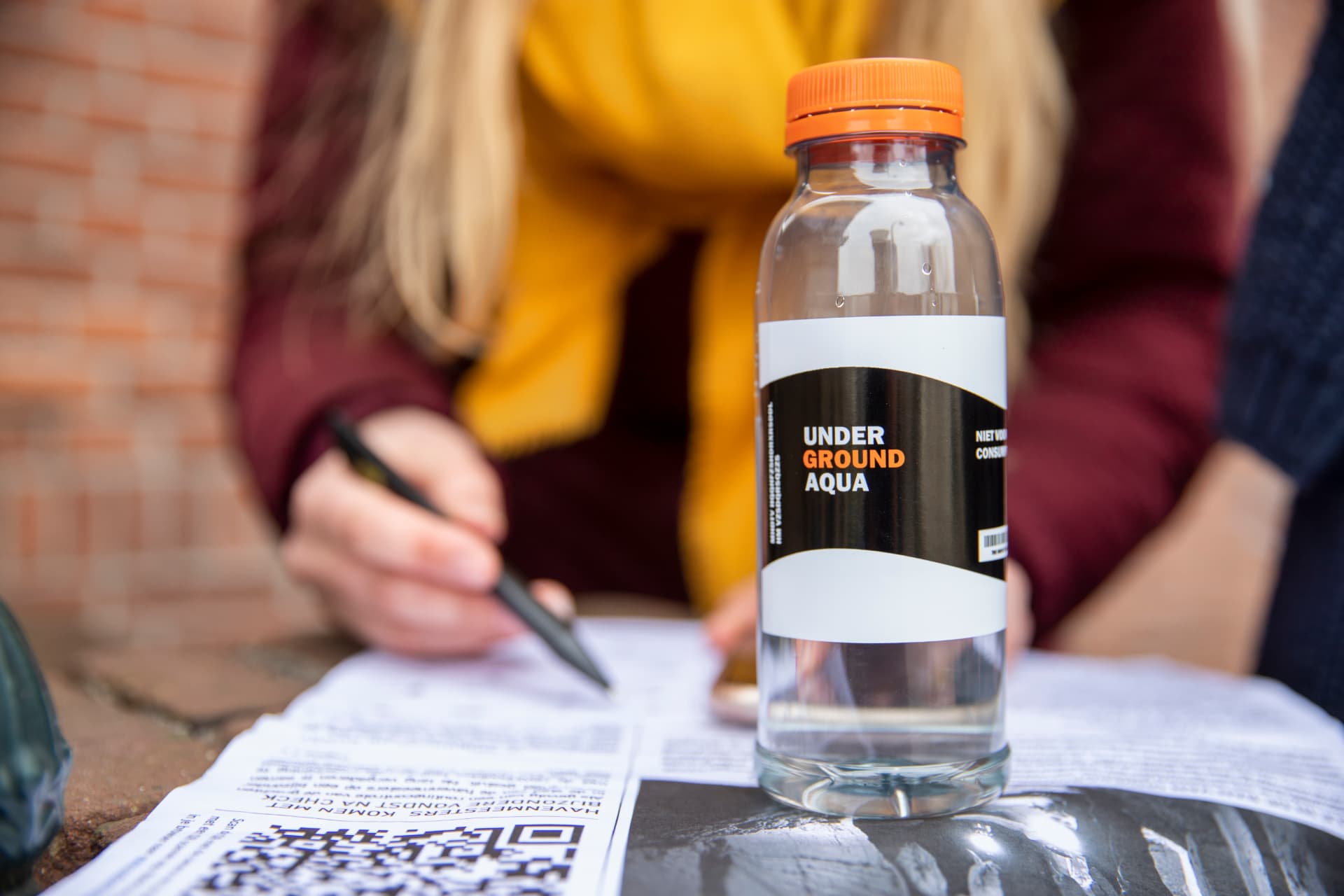 Deelnemers van de buiten game The Undergrounds vullen opdrachten in, met de Underground Aqua-fles op tafel